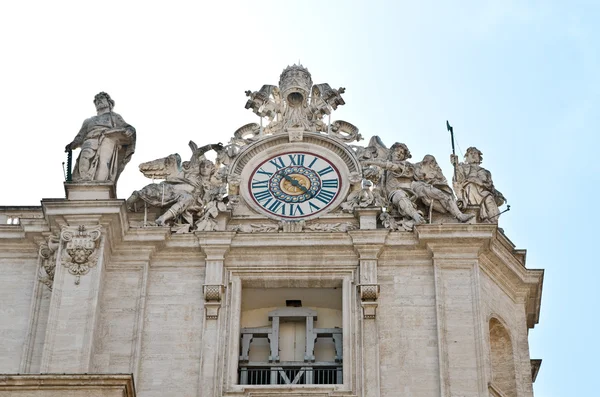 Klok en standbeeld op dak van St. Peter's Basiliek tegen de blauwe hemel. — Stockfoto