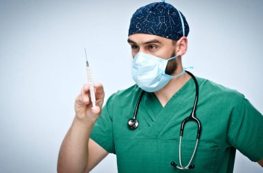 Yeşil cerrahi takım elbise ve şapka tıp bir şırınga tutarak erkek doktor.