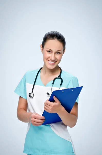 Молодая женщина врач в униформе с черным детским стетоскопом держит синюю табличку для бумаг . — стоковое фото
