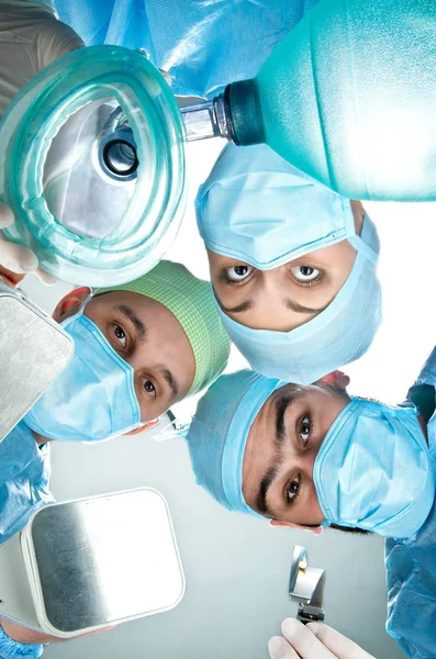 Tres anestesiólogos en quirófano con máscara de oxígeno, desfibrilador y cuchilla para intubación . —  Fotos de Stock