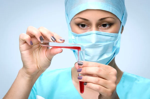 Doctor sosteniendo un tubo de vidrio con la droga. Médico con gorra quirúrgica y máscara quirúrgica . —  Fotos de Stock