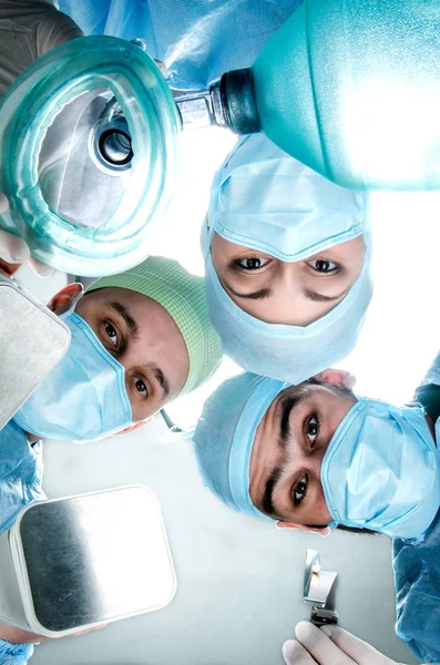 Tres doctores en el costo de operación del paciente. Médico con trajes quirúrgicos, máscaras y guantes . —  Fotos de Stock