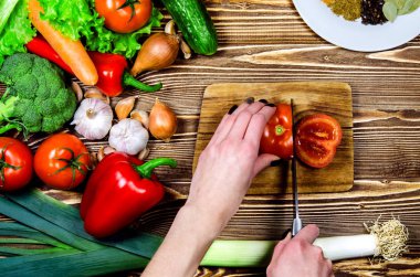 Şef salata taze domates bir dilim kes. Sonraki ahşap yüzeyler üzerinde taze sebze ve baharatlar vardır.