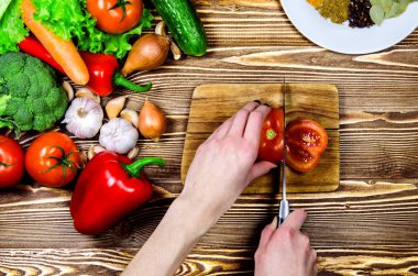 Şef salata taze domates bir dilim kes. Yakınlarda taze sebze ve baharat bulunmaktadır.