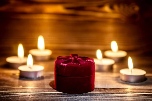 Caixa vermelha com um anel no fundo de queimar pequena vela . — Fotografia de Stock
