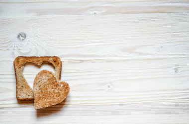 Beyaz ahşap yüzeyde eksizyon ile tost kalbinde yer almaktadır. Tost üstte düzensiz bir tahıl kalp yatıyor.