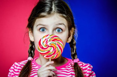 Büyük renkli karamelli şeker tutan büyük güzel yeşil gözlü kız.