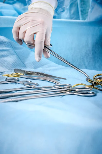 Operační sestra bere svorku ze stolu lékařských přístrojů. — Stock fotografie