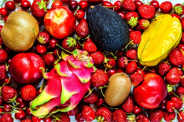 Спелые фрукты Карамбола, персик, авокадо, драконьи фрукты среди ягод клубники и сладкой вишни . — стоковое фото