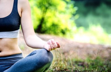 Genç bir kız lotus poz oturan yoga keyif alıyor.