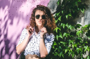 Üzüm ile büyümüş bir renkli duvar arka plan üzerinde siyah gözlüklü genç bir kız.