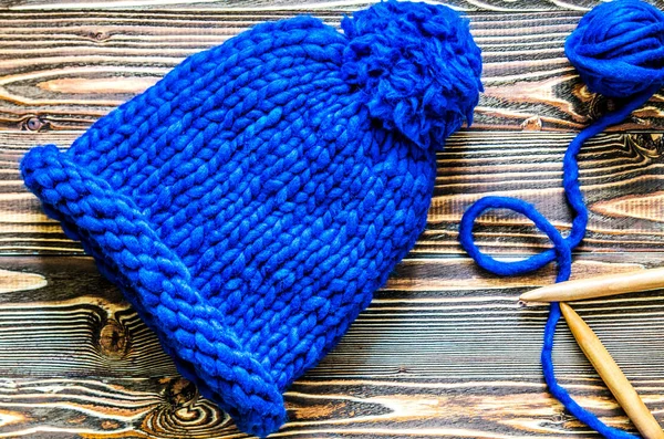 Blue knitted cap of merino wool, bamboo knitting needles and a tangle of thread.