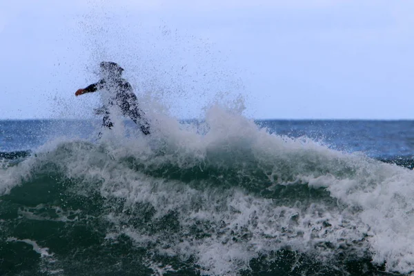 Surfing - riding athletes on a wave on special light boards.