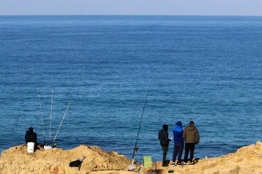balıkçı kıyıda oturur ve balık yakalar 