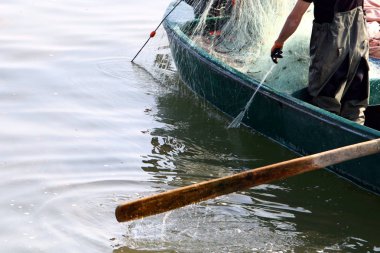 balıkçı kıyıda oturur ve balık yakalar 