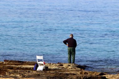 balıkçı kıyıda oturur ve balık yakalar 