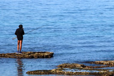 balıkçı kıyıda oturur ve balık yakalar 