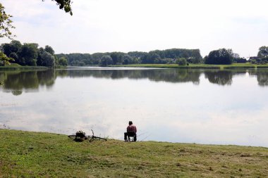 balıkçı kıyıda oturur ve balık yakalar 