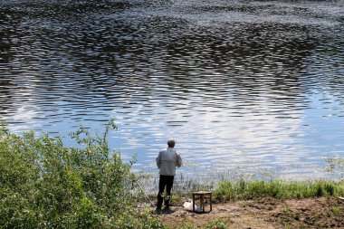 balıkçı kıyıda oturur ve balık yakalar 