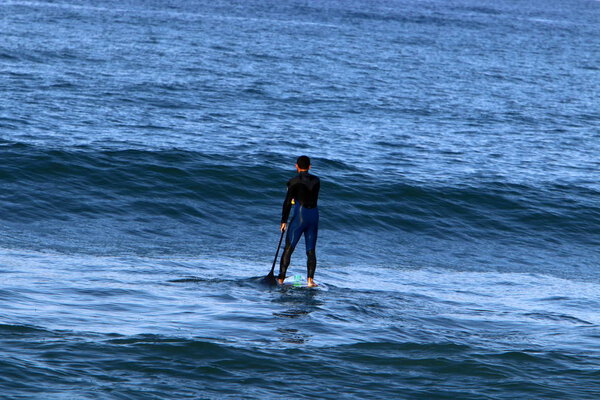 Surfing - riding the waves on special sports boards in the Mediterranean Sea in northern Israel 