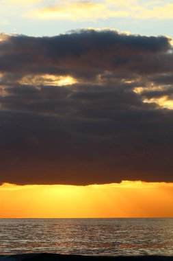 Kuzey İsrail'de Akdeniz'de ufukta güneş batıyor, gündüz bitiyor ve gece çöküyor 