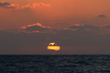 Kuzey İsrail'de Akdeniz'de ufukta güneş batıyor, gündüz bitiyor ve gece çöküyor 