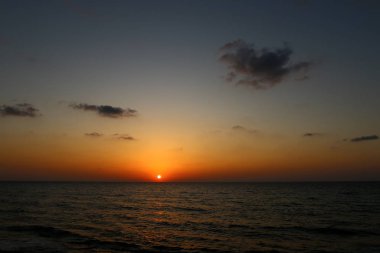 Kuzey İsrail'de Akdeniz'de ufukta güneş batıyor, gündüz bitiyor ve gece çöküyor 