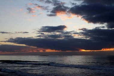 Kuzey İsrail'de Akdeniz'de ufukta güneş batıyor, gündüz bitiyor ve gece çöküyor 