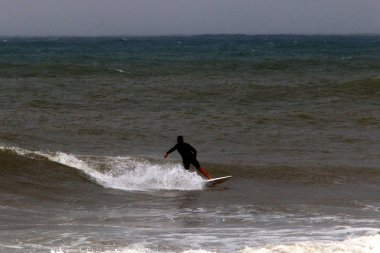 İsrail 'in kuzeyindeki Akdeniz' deki bir fırtına sırasında büyük dalgalarda sörf yapmak. 