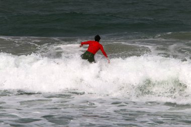 Sporcu, İsrail 'in kuzeyindeki Akdeniz' de dalgalarda sörf yapıyor. İsrail 'de sıcak yaz 