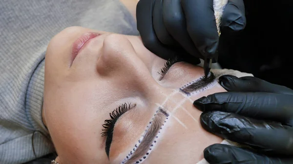 Permanent makeup. Permanent tattooing of eyebrows. Cosmetologist applying permanent make up on eyebrows- eyebrow tattoo.