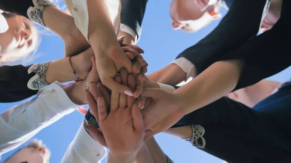 Happy friends graduates join hands together. The concept of a friendly team.