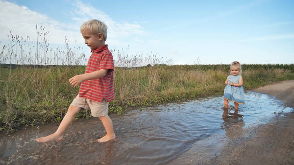 Little funny children run through the puddles.