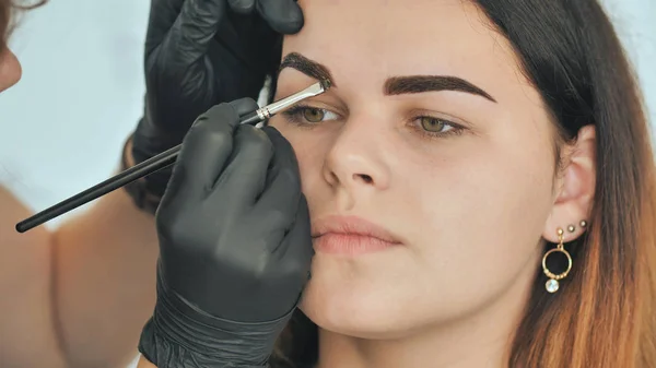Permanent makeup. Permanent tattooing of eyebrows. Cosmetologist applying permanent make up on eyebrows - eyebrow tattoo.