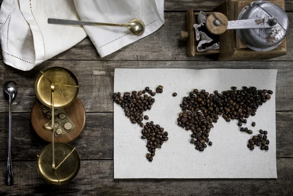 Kaart van de wereld, bekleed met koffiebonen op oud papier. Eurazië, Amerika, Australië, Afrika. Vintage. Zwarte koffie, gemalen koffie, schalen, oude rot grinder op oude houten tafel. bovenaanzicht. plat lag — Stockfoto