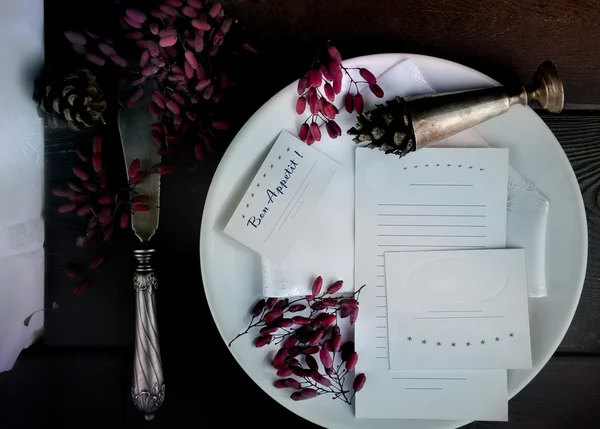 Witte plaat met oude zilveren mes, glas en vellen papier op een houten achtergrond. ruimte voor tekst. bovenaanzicht — Stockfoto