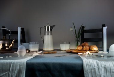 Natürmort. rustik yemek. süt kabı, mumlar, çay, yumurta, ekmek masada ekmek