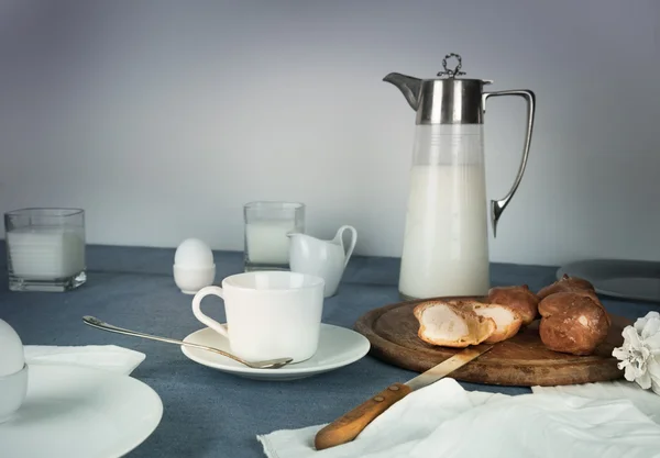 Natürmort. rustik yemek. süt kabı, mumlar, çay, yumurta, ekmek masada ekmek — Stok fotoğraf