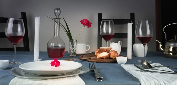 Still life. rose wine in glasses, bun, white candles on a blue tablecloth — Stock Photo, Image