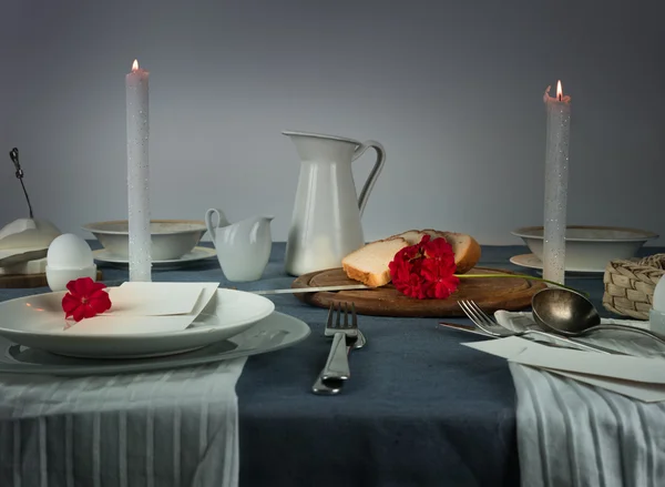 Натюрморт. глечик, булочка, білі свічки на синій скатертині — стокове фото