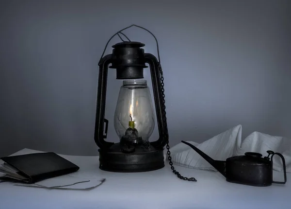 Lâmpada de querosene, caldeira, um caderno sobre a mesa no crepúsculo — Fotografia de Stock