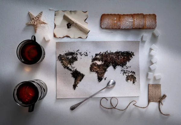 茶葉と並んで、世界の地図。ユーラシア大陸、アメリカ、オーストラリア、アフリカ。ヴィンテージ。タオル、砂糖、メモ、クラッカー、スプーン。平面図です。フラット レイアウト — ストック写真