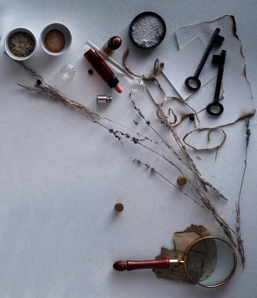 jars of powders, leaves burnt paper, magnifier, scales on the table. top view