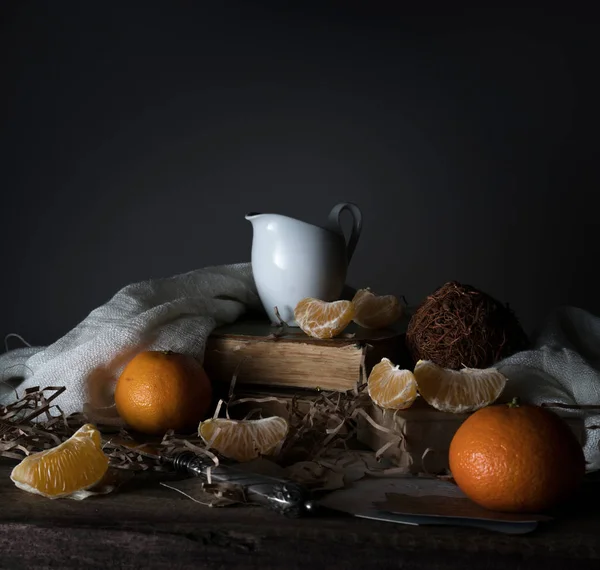 Bodegón, vintage. mandarinas, rebanadas de mandarina, leche, bufanda y cuchillo de plata viejo en una mesa de madera . — Foto de Stock