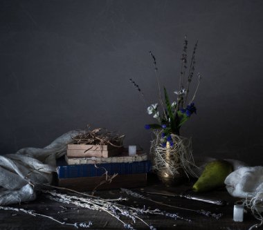 Natürmort, vintage. eski kitaplar, buket çiçek, perdelik ahşap bir masa üzerinde. koyu arka planlar