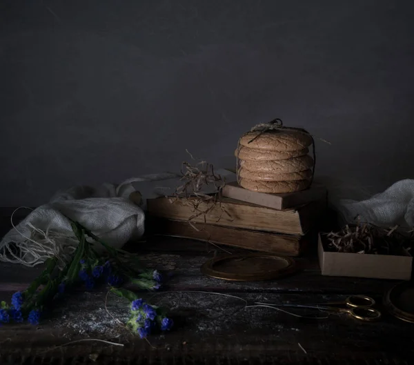 Stilleven, vintage. oude boeken, korenbloemen, taarten, gordijnen op een houten tafel — Stockfoto