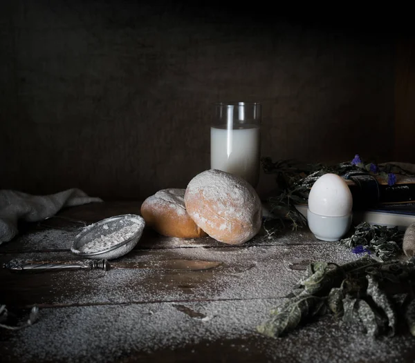 Ainda vida, vintage. um pequeno-almoço simples. leite, ovos, pão branco, farinha na mesa de madeira. fundo escuro . — Fotografia de Stock