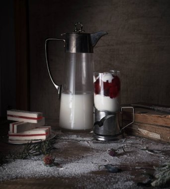 rustik natürmort, vintage. koyu arka plan. bir eski sürahi ve tatlı bir bardak süt. ahşap masa.