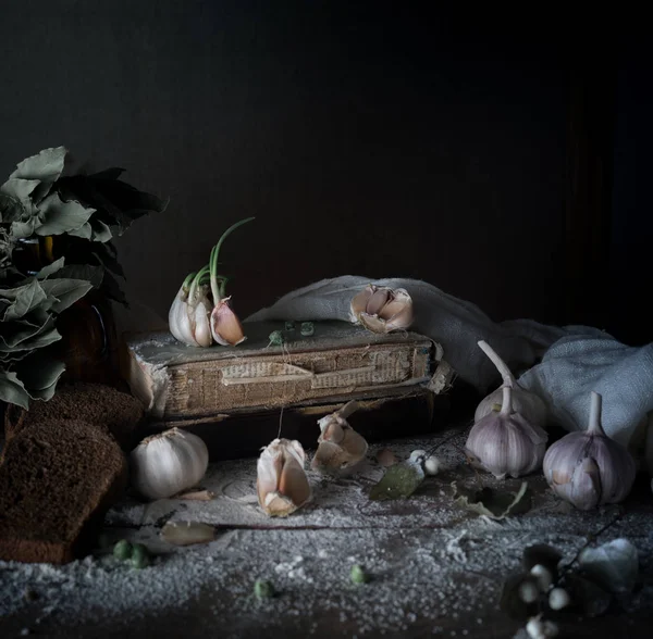 Naturaleza muerta rústica, vintage. ajo, pan de centeno, harina y libros antiguos sobre una mesa de madera — Foto de Stock