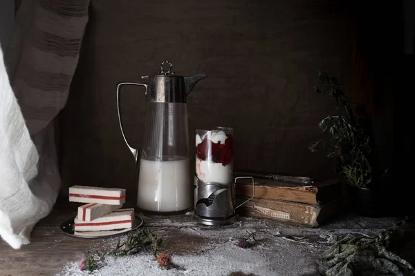 Rustieke stilleven, vintage. donkere achtergrond. melk in een oude kruik en dessert in een glas. houten tafel. — Stockfoto